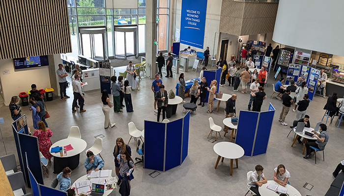 birds eye view of the college atrium at an open event, with course stands and visitors