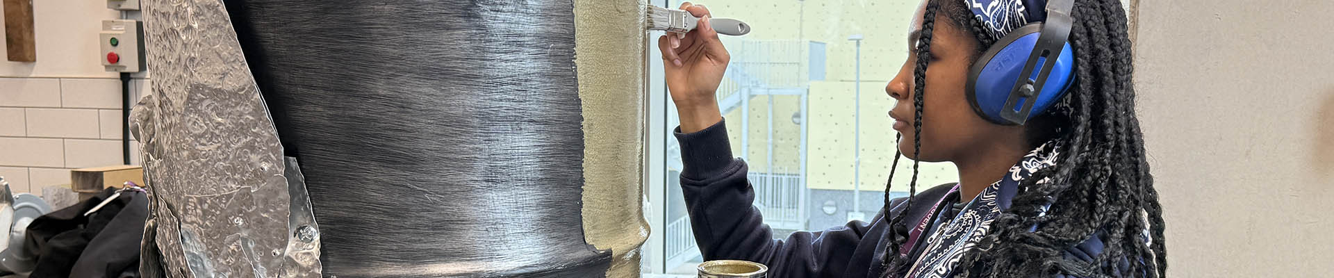 Richmond upon Thames Art  student, in the studio, painting a metal drum gold as part of her part project. 