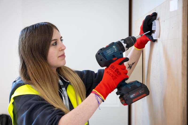 Electrical installation female student with  cordless electric screwdriver