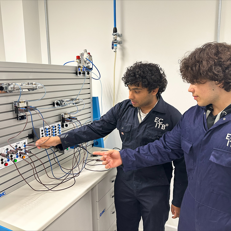Two Richmond students working on electro-pneumatics together, wearing ECITB blue overalls.