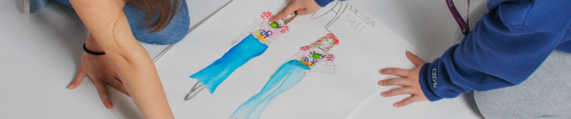 Two Richmond upon Thames Fashion Students looking at design drawings. 