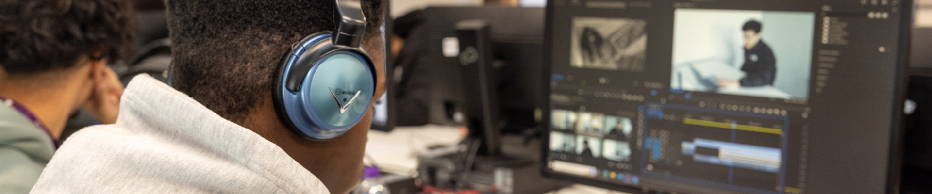 male student with headphones on using editing software on computer