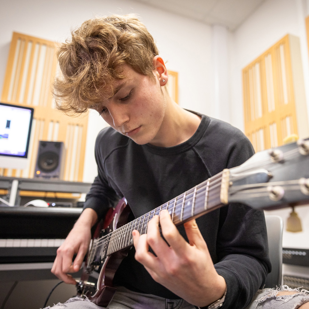 male student plating guitar