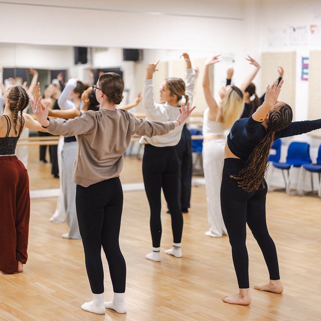 Richmond upon Thames dances in the dance studio. They are facing the mirrors and bar and their arms are out stretched.