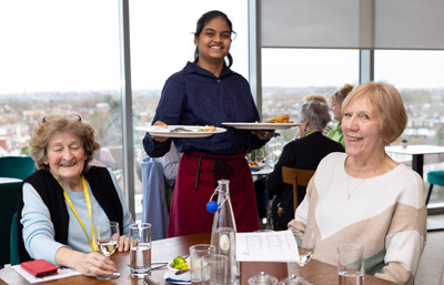 Hospitality student serving two customers in the View Training Restaurant