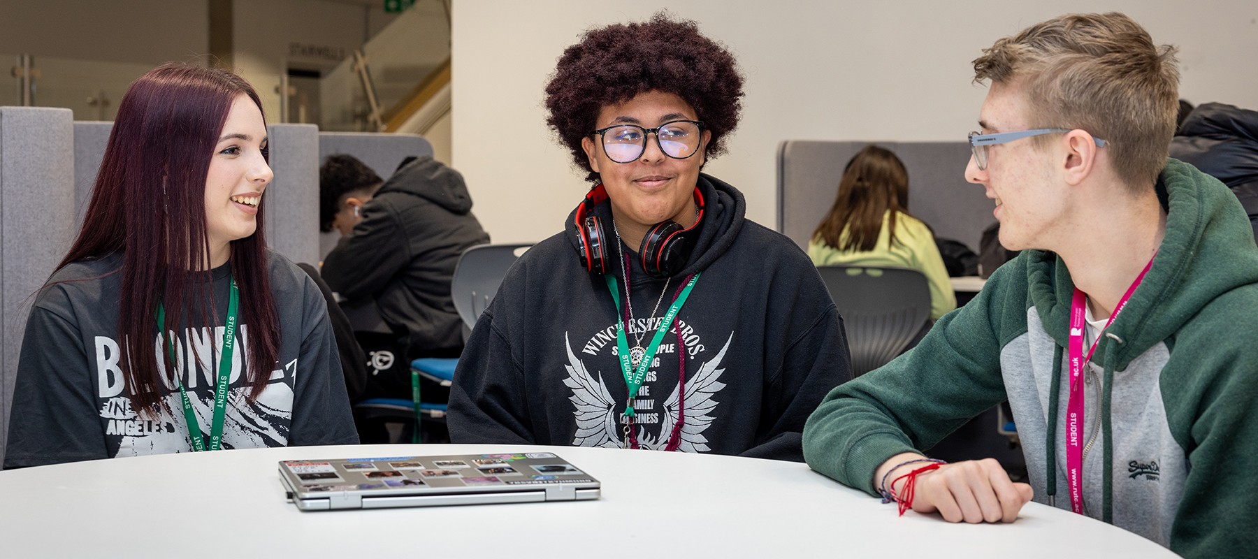 Three Richmond upon Thames College students sitting at a table talking to each other. 