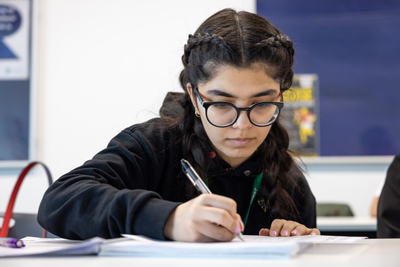 female student writing on paper with pen