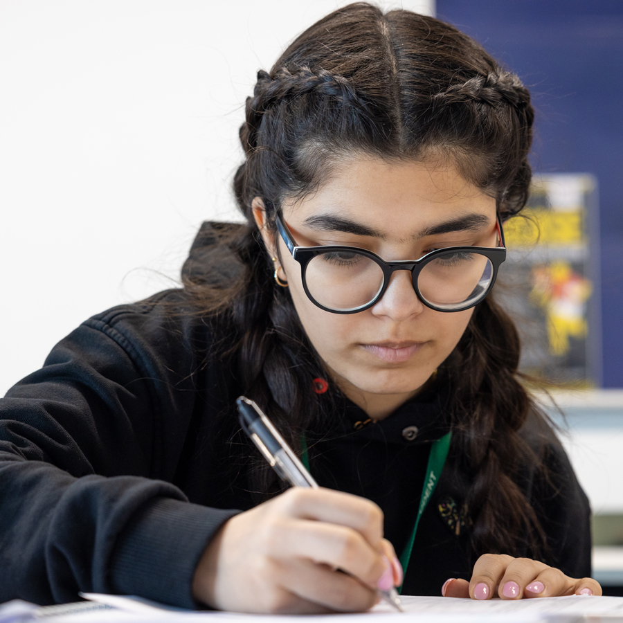 female student writing with a pen on paper