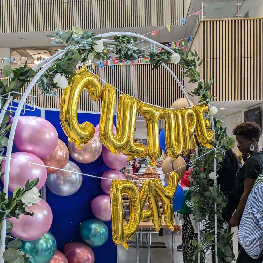 Gold balloons suspended from a flowered archway spelling 'Culture Day'