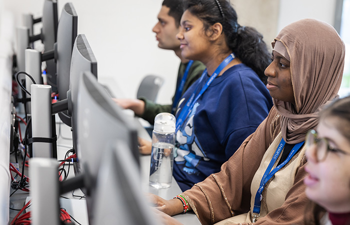 Richmond upon Thames students are sitting at a row of computers looking at the screens with their hands resting on the mouse or keyboard.