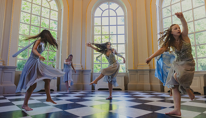 Richmond upon Thames College dance students performing at the Orleans House Gallery. There are large windows around the space with a checkered flooring.