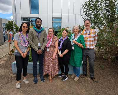 6 foundation learning staff standing in a line in the garden in front of the college building