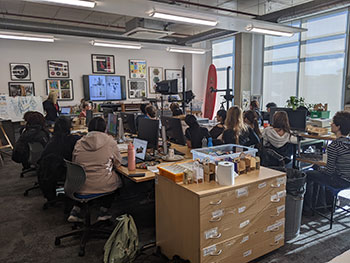 Architecture students sitting in a classroom looking at the interactive screen, having a talk from Gareth Box of Blue Zoo Animation Studio