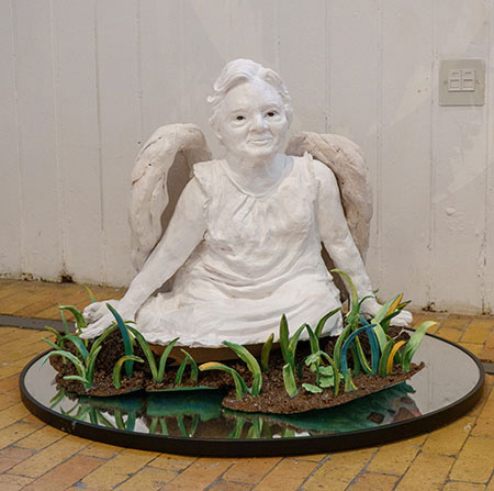 'Generations Apart' - it is a ceramic statue of a woman with wings sitting in a garden