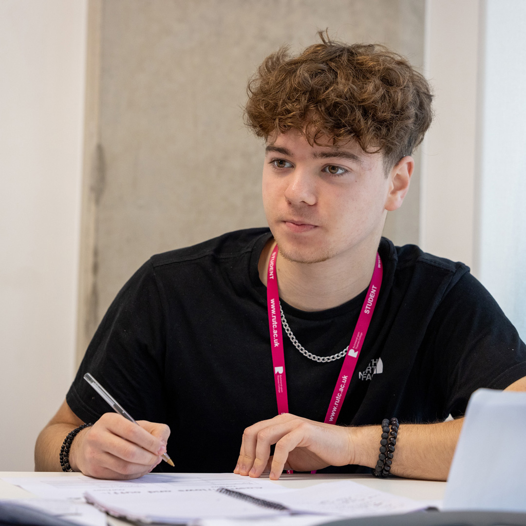 male student taking notes in lesson