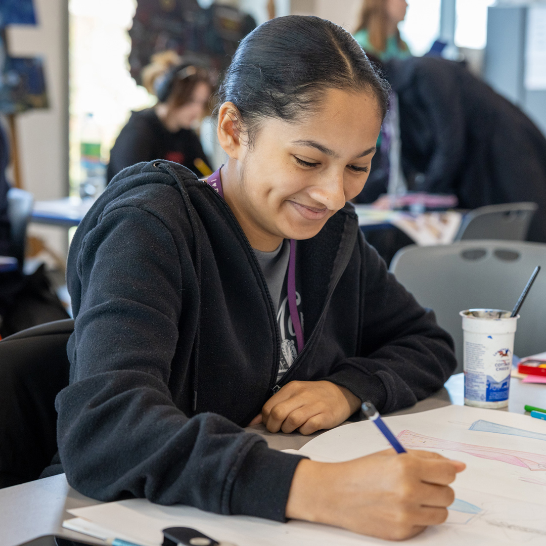 female student drawing and smiling
